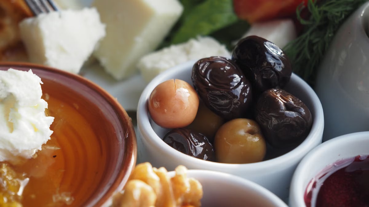 A close-up view of a Mediterranean breakfast with cheese, olives, and honey.